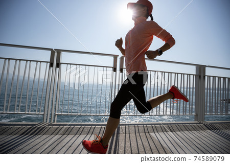Healthy lifestyle fitness sports woman runner running on seaside trail Healthy lifestyle fitness sports woman runner running on seaside trail 74589079