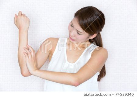 一名婦女過敏和撓她的手臂。 一名婦女過敏和撓她的手臂。 74589340