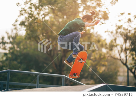 Asian woman skateboarder skateboarding at skatepark Asian woman skateboarder skateboarding at skatepark 74589715