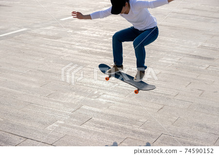 Asian woman skateboarder skateboarding in modern city Asian woman skateboarder skateboarding in modern city 74590152