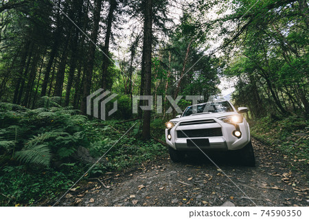 Driving offroad car on trail in high altitude forest mountain 74590350