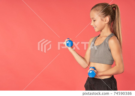 Cute sporty girl doing exercise with dumbbells 74590386