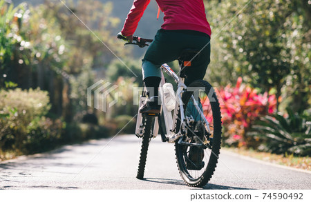 Woman riding a bike on tropical park trail in spring 74590492