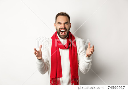 Christmas holidays and New Year concept. Angry man looking with hatred and shaking hands mad, yelling at someone, standing furious against white background Christmas holidays and New Year concept. Angry man looking with hatred and shaking hands mad, yelling at someone, standing furious against white background 74590917