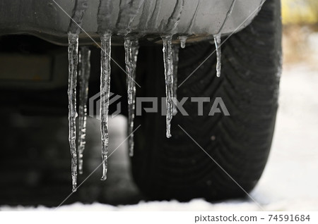 Beautiful icicles on the car. Concept for winter and dangerous winter traffic of cars on the road. Beautiful icicles on the car. Concept for winter and dangerous winter traffic of cars on the road. 74591684