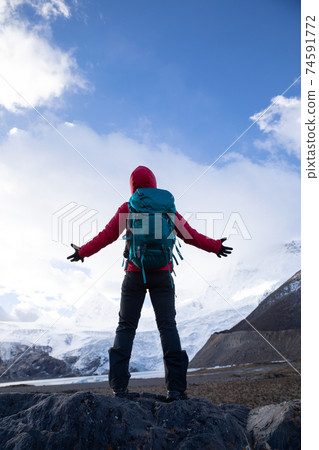 Successful woman backpacker hiking in winter mountains 74591772