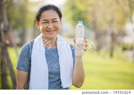 Happy senior woman holding bottle after drink water exercise in garden, relax and exercise concept. Happy senior woman holding bottle after drink water exercise in garden, relax and exercise concept. 74591824