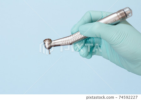 Dentist's hand in glove with dental handpiece. 74592227