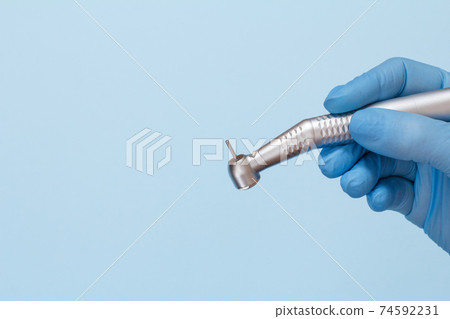 Dentist's hand in glove with dental handpiece. Dentist's hand in glove with dental handpiece. 74592231