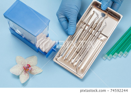 Dentist's hands with set of metal dental instruments for teeth dental care Dentist's hands with set of metal dental instruments for teeth dental care 74592244