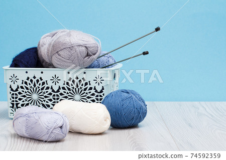 Woolen yarn for knitting. Balls of natural wool yarn and knitting needles Woolen yarn for knitting. Balls of natural wool yarn and knitting needles 74592359