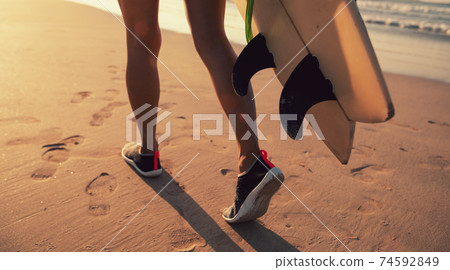 Woman surfer with surfboard ready to surf on a beach 74592849