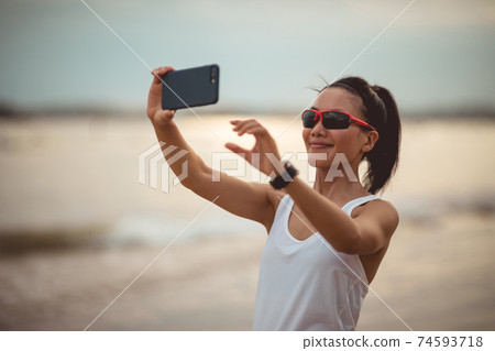 Woman taking selfie with smartphone on beach 74593718