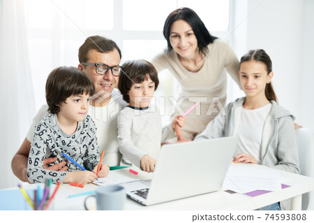 Spend days with people you love. Happy latin family with children spending time together at home. Father watching cartoons together with kids while using laptop Spend days with people you love. Happy latin family with children spending time together at home. Father watching cartoons together with kids while using laptop 74593808