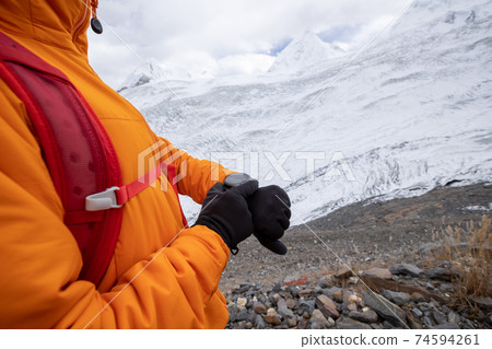 Woman hiker checking the altitude on sports watch on winter mountain top Woman hiker checking the altitude on sports watch on winter mountain top 74594261