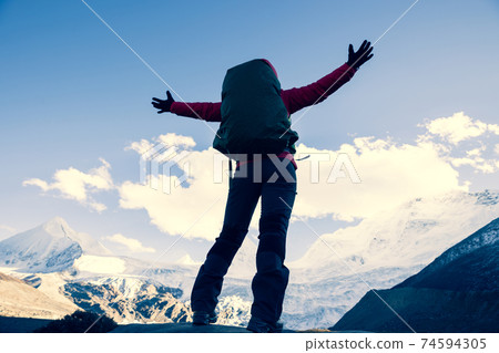 Successful woman backpacker hiking in winter mountains 74594305