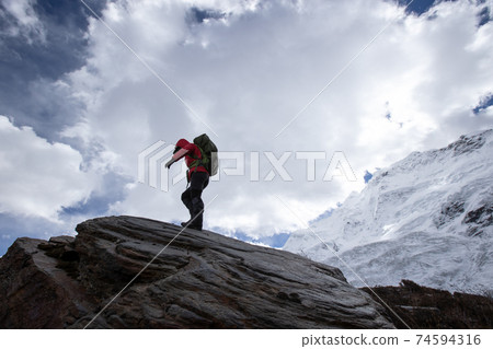 Woman hiker walking on winter mountain top cliff edge 74594316
