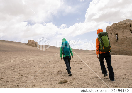 Two women hikers hiking on sand desert 74594380