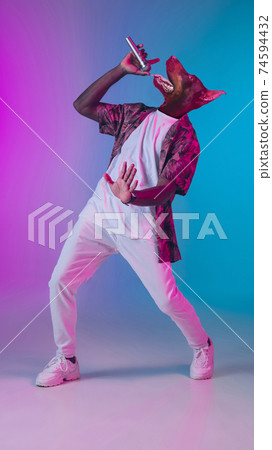 Talented dog, professional musician performing on multicoloted background in neon light. Concept of music, hobby, festival, contemporary art collage. Modern design. Talented dog, professional musician performing on multicoloted background in neon light. Concept of music, hobby, festival, contemporary art collage. Modern design. 74594432