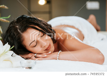 Beautiful young woman in the massage salon with brown curly hair and healthy skin. Masseur and patient concept. Beautiful young woman in the massage salon with brown curly hair and healthy skin. Masseur and patient concept. 74595372