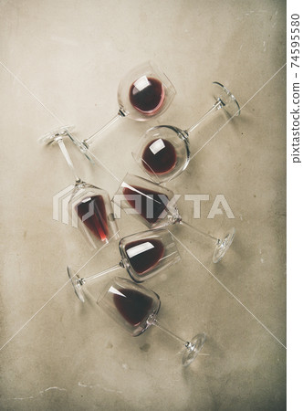 Flat-lay of red wine in glasses over grey Flat-lay of red wine in glasses over grey 74595580