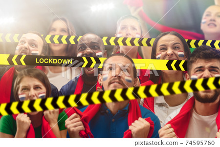 Netherlands soccer fans cheering for favourite sport team with bright emotions, excited, wondered behind the limiting tapes with Lockdown 74595760