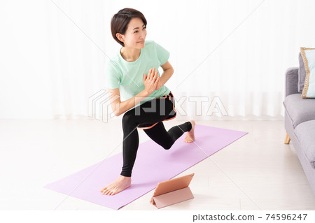Middle-aged woman doing online yoga at home 74596247