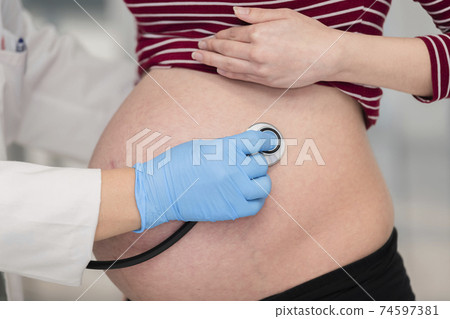 Doctor checking a pregnant woman with a stethoscope 74597381