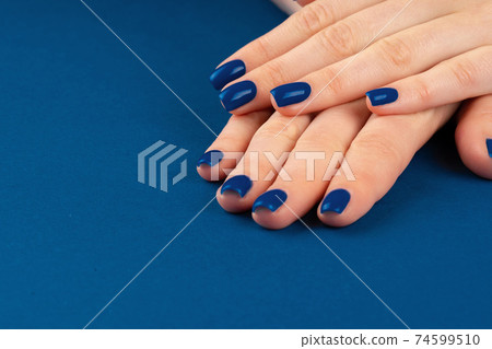 Female hands with manicure of classic blue color on blue background 74599510