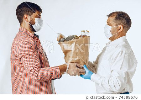 Delivery man in face mask and gloves. Food delivery, online shopping concept while coronavirus pandemia 74599676