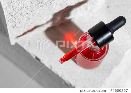 Glass jar of skincare serum on concrete block 74600267