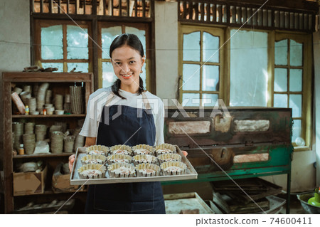 Close up of a pretty Asian girl carrying a baking sheet filled with several small cookie cutters Close up of a pretty Asian girl carrying a baking sheet filled with several small cookie cutters 74600411