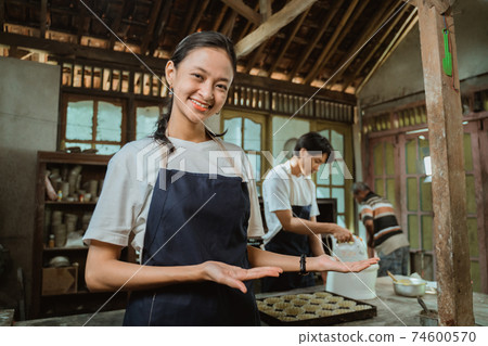 Beautiful employee in apron offering you something from her palms 74600570