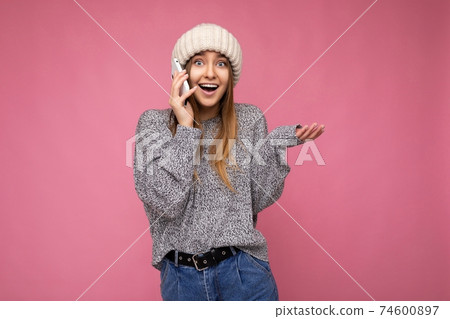 Attractive positive happy surprised young blonde woman wearing casual grey sweater and beige hat 74600897