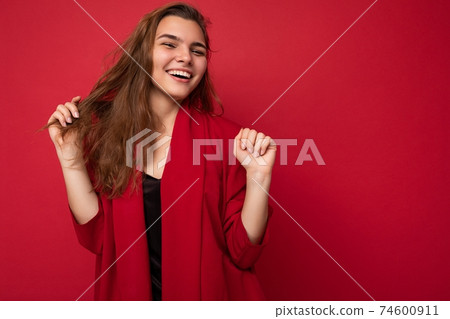 Portrait of positive cheerful fashionable woman in formalwear looking at camera isolated on red 74600911