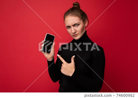 Angry sad attractive positive young brunette woman wearing black sweater standing isolated over red 74600982