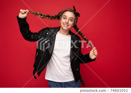 Shot of pretty positive smiling brunette little female teenager with pigtails wearing stylish black 74601052