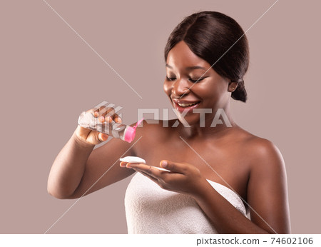 Face Cleansing Concept. Attractive Black Lady Pouring Micellar Water On Cotton Pad 74602106