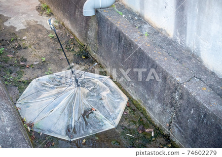 A photo of a vinyl umbrella abandoned on the road. Image of environmental and social issues. 74602279