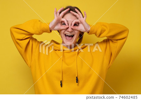 Young caucasian woman showing ok sign on eyes. Young caucasian woman showing ok sign on eyes. 74602485