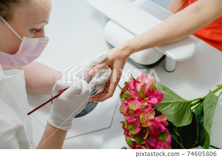Nail artist working with a woman client Nail artist working with a woman client 74605806
