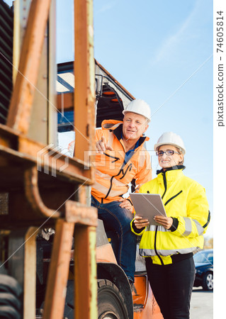 Supervisor instructing forklift driver what to work on next 74605814