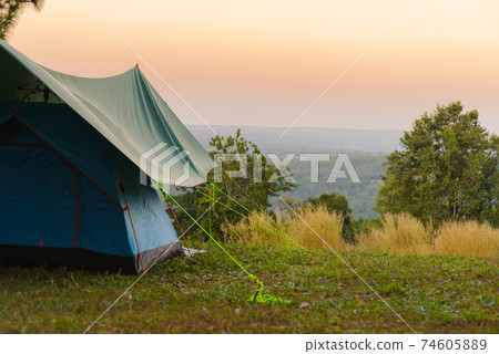 Tourist tent on among meadow in the sunset overlooking mountains. outdoors camping Tourist tent on among meadow in the sunset overlooking mountains. outdoors camping 74605889