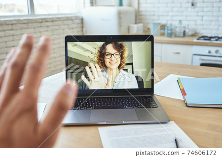 Close up of laptop screen with attractive female teacher smiling and waving at student during video call, having online lesson during quarantine lockdown Close up of laptop screen with attractive female teacher smiling and waving at student during video call, having online lesson during quarantine lockdown 74606172