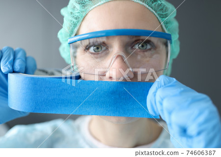 Woman doctor sealing her mouth with blue tape Woman doctor sealing her mouth with blue tape 74606387