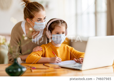 Mother and kid in protective masks with laptop doing homework together 74607985