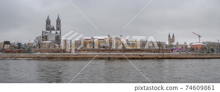 Panoramic view over Magdeburg historical downtown in Winter with icy trees and snow during foggy day and dramatic sky, Germany. 74609861