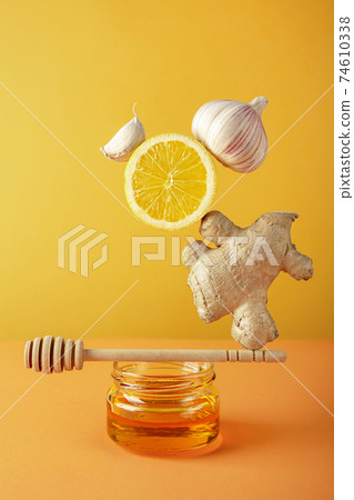 Floating food balance equilibrium with set of ingredients for making drinks to support immune system and prevent diseases honey, ginger and lemon on yellow background. Alternative herbal medicine. Floating food balance equilibrium with set of ingredients for making drinks to support immune system and prevent diseases honey, ginger and lemon on yellow background. Alternative herbal medicine. 74610338