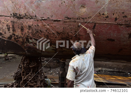 Dhaka, Bangladesh, Shodrugat, a mechanic repairing an old passenger ship, hitting the hull with a hammer 74612101