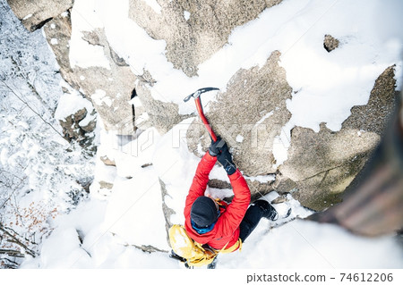 Top view of a man climbing the rocks with an ice ax. Top view of a man climbing the rocks with an ice ax. 74612206